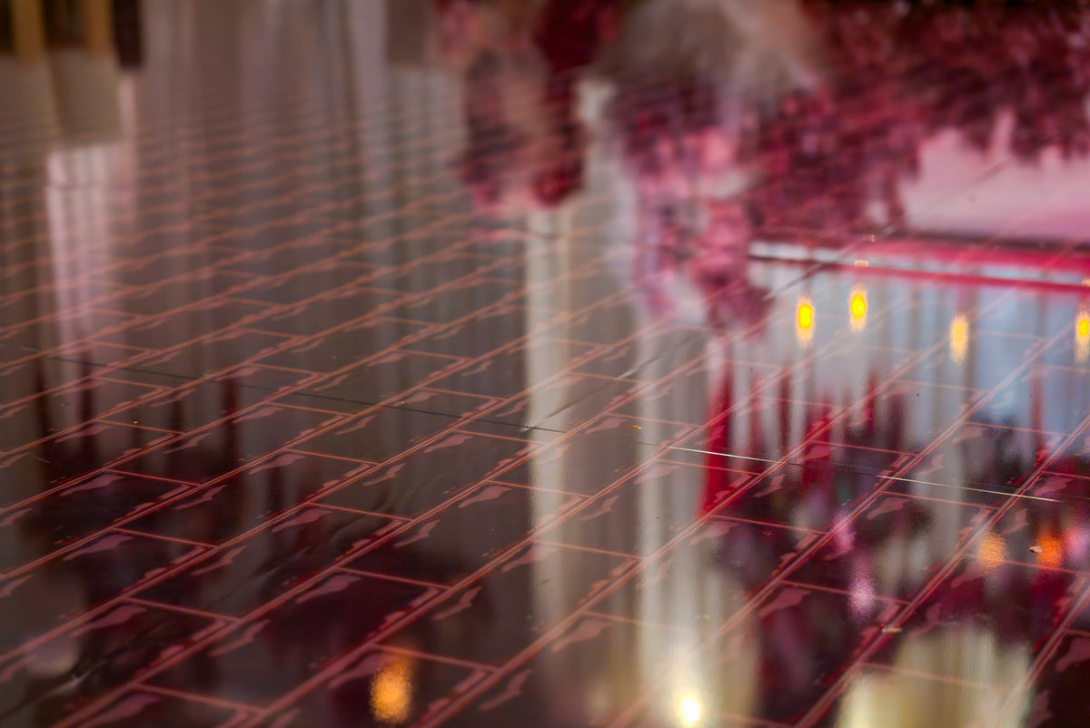 Close-up of red geometric lines on a reflective dance floor with warm event-light reflections.